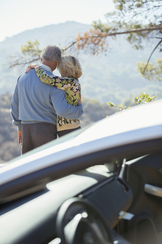 Älteres Paar mit Blick auf die Berge außerhalb des Autos, lizenzfreies Stockfoto