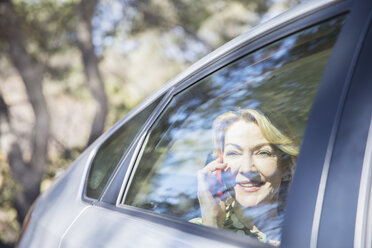 Senior woman talking on cell phone in car - CAIF16937