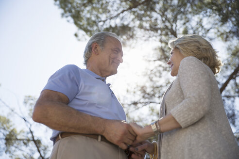 Glückliches älteres Paar hält Hände unter einem Baum - CAIF16938