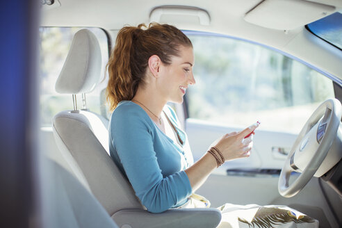 Frau textet mit Handy im Auto - CAIF16944