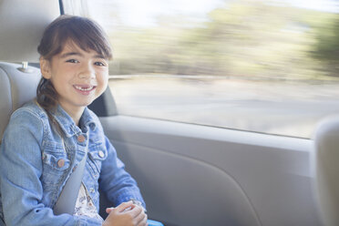 Portrait of happy girl in back seat of car - CAIF16960