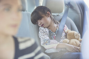 Mädchen mit Teddybär schlafend auf dem Rücksitz eines Autos - CAIF16961