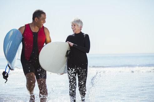 Älteres Paar mit Surfbrettern am Strand - CAIF16967