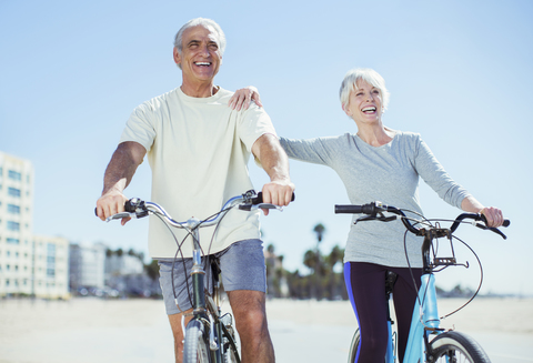 Älteres Paar mit Fahrrädern am Strand, lizenzfreies Stockfoto