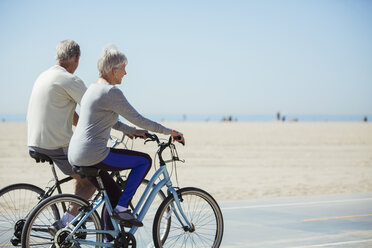 Älteres Paar fährt mit dem Fahrrad am Strand - CAIF16972