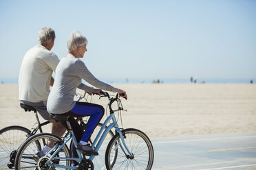 Senior couple riding bicycles on beach - CAIF16972