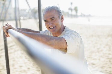 Porträt eines älteren Mannes, der sich am Strand auf eine Stange stützt - CAIF16981