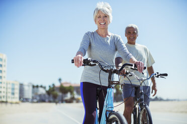 Porträt eines älteren Paares mit Fahrrädern an der Strandpromenade - CAIF16989