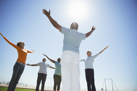 Senioren üben Yoga unter sonnigem blauem Himmel, lizenzfreies Stockfoto