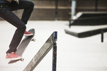 Low section of man performing skateboard stunt at skateboard park - CAVF08854