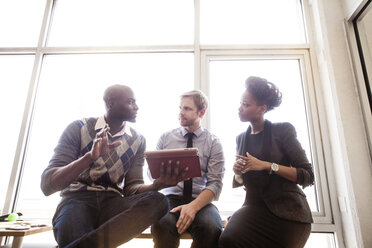 Business people discussing while looking at tablet in office - CAVF08938