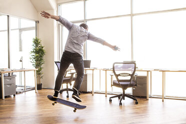 Rear view of man skateboarding at office - CAVF08946