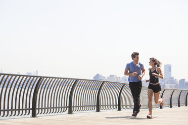 Paar joggt am Geländer gegen den Himmel - CAVF08983