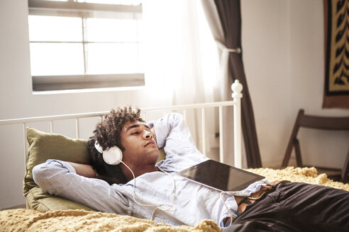 Mann hört Musik beim Entspannen auf dem Bett - CAVF09024