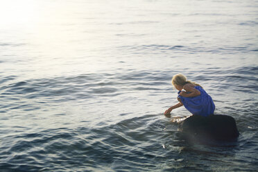 Mädchen hockt auf einem Felsen im Meer - CAVF09034