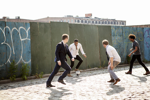 Männer spielen Fußball an einer Mauer auf der Straße, lizenzfreies Stockfoto