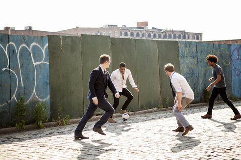 Männer spielen Fußball an einer Mauer auf der Straße - CAVF09057