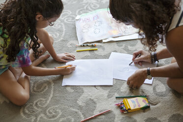 Hochformatige Ansicht von Mutter und Tochter beim Zeichnen auf Papier zu Hause - CAVF09076