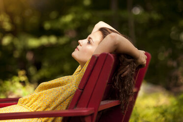 Side view of woman relaxing on lounge chair - CAVF09119