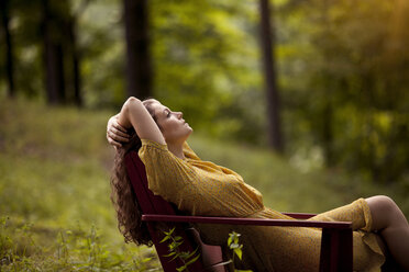Woman relaxing on lounge chair in filed - CAVF09120
