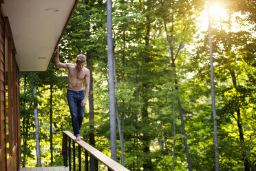 Shirtless boy walking on railing in balcony - CAVF09127