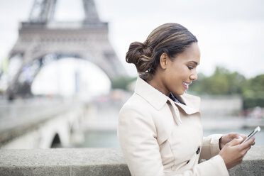 Geschäftsfrau mit Mobiltelefon in der Nähe des Eiffelturms, Paris, Frankreich - CAIF17013