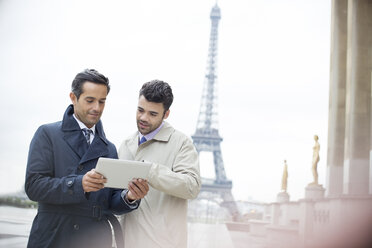 Businessmen using digital tablet near Eiffel Tower, Paris, France - CAIF17016