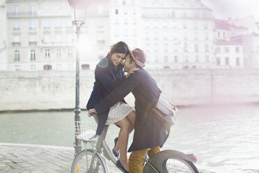 Sich umarmendes Paar auf dem Fahrrad entlang der Seine, Paris, Frankreich - CAIF17029