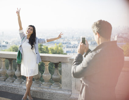 Man photographing girlfriend with city in background - CAIF17045