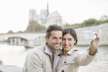 Couple taking self-portrait along Seine River near Notre Dame Cathedral, Paris, France - CAIF17069