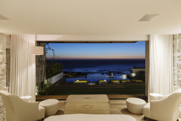 Modern bedroom overlooking ocean at night - CAIF17108