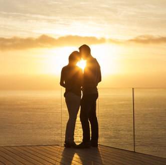 Silhouette eines Paares bei Sonnenuntergang über dem Meer - CAIF17142