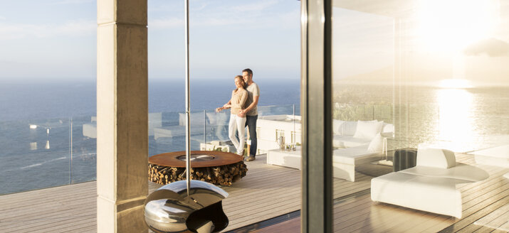 Pärchen auf modernem Balkon mit Blick aufs Meer - CAIF17178
