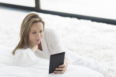 Frau im Bademantel mit digitalem Tablet im Schlafzimmer - CAIF17180