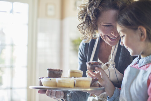 Grandmother offering granddaughter cupcakes - CAIF17272