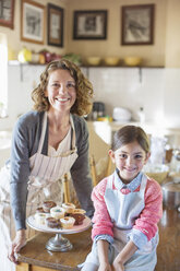 Grandmother and granddaughter smiling in kitchen - CAIF17291