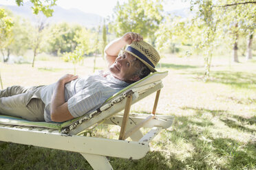 Älterer Mann entspannt sich auf einem Liegestuhl im Freien - CAIF17300