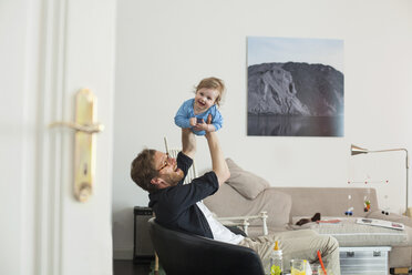 Vater hebt seine Tochter im Wohnzimmer hoch - KVF00099