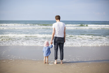Netherlands, Renesse, father and daughter standing at beach - KVF00108
