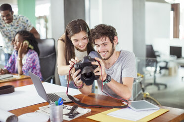 Menschen, die gemeinsam Fotos im Büro betrachten - CAIF17310