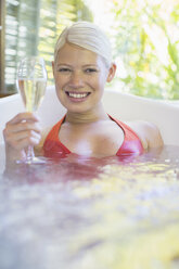 Woman drinking white wine in hot tub - CAIF17350