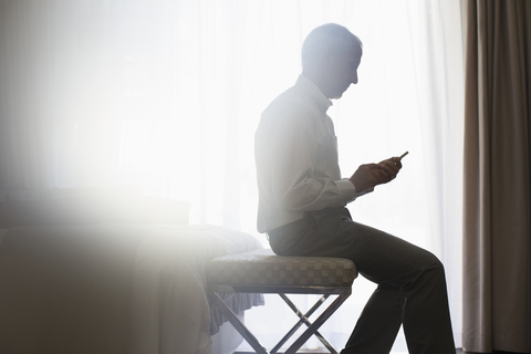 Silhouette eines Mannes, der ein Mobiltelefon benutzt, lizenzfreies Stockfoto