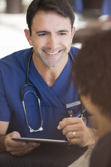 Porträt eines lächelnden erwachsenen Arztes, der einen Tablet-PC hält - CAIF17394