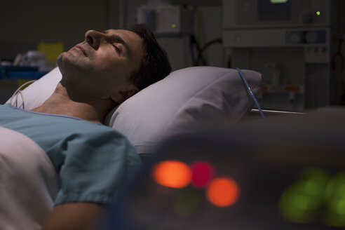 Patient im Krankenhausbett auf der Intensivstation, medizinische Geräte im Vordergrund - CAIF17410