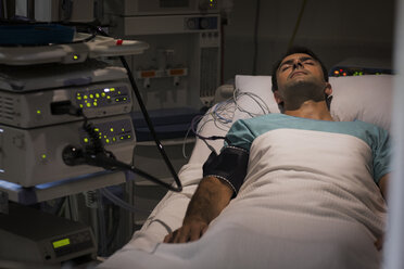 Patient im Bett liegend, angeschlossen an ein Überwachungsgerät auf der Intensivstation - CAIF17411