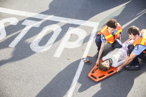 Sanitäter untersuchen verletztes Mädchen auf der Straße, lizenzfreies Stockfoto