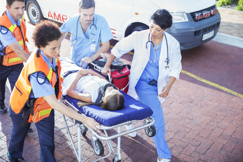 Arzt, Krankenschwester und Sanitäter transportieren einen Patienten auf einer Bahre, lizenzfreies Stockfoto