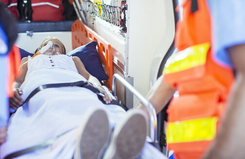 Sanitäter untersuchen einen Patienten auf einer Bahre im Krankenwagen - CAIF17426
