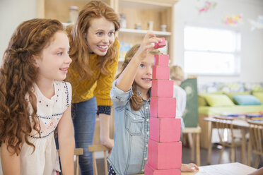 Schüler und Lehrer stapeln Blöcke im Klassenzimmer - CAIF17457