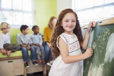 Schülerin zeichnet auf Kreidetafel im Klassenzimmer - CAIF17458